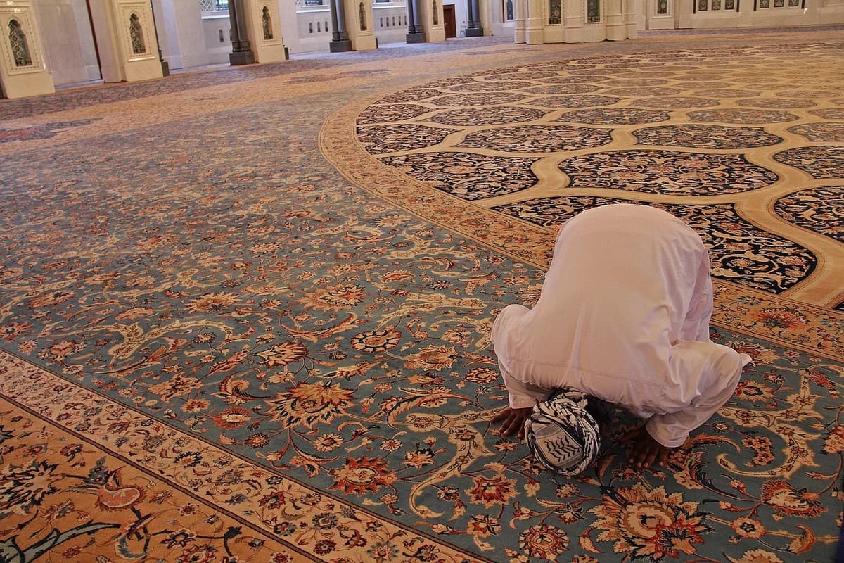 A person praying inside an ornate mosque.