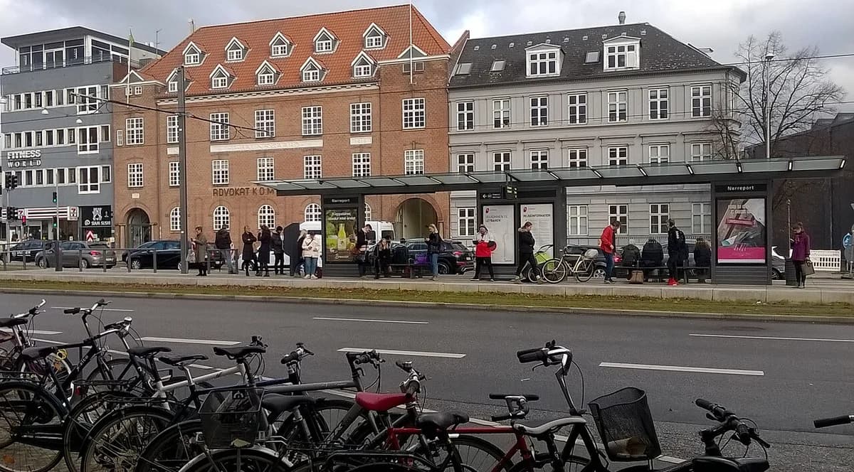 Nørreport Station bus stop in central Aarhus with people and bicycles.