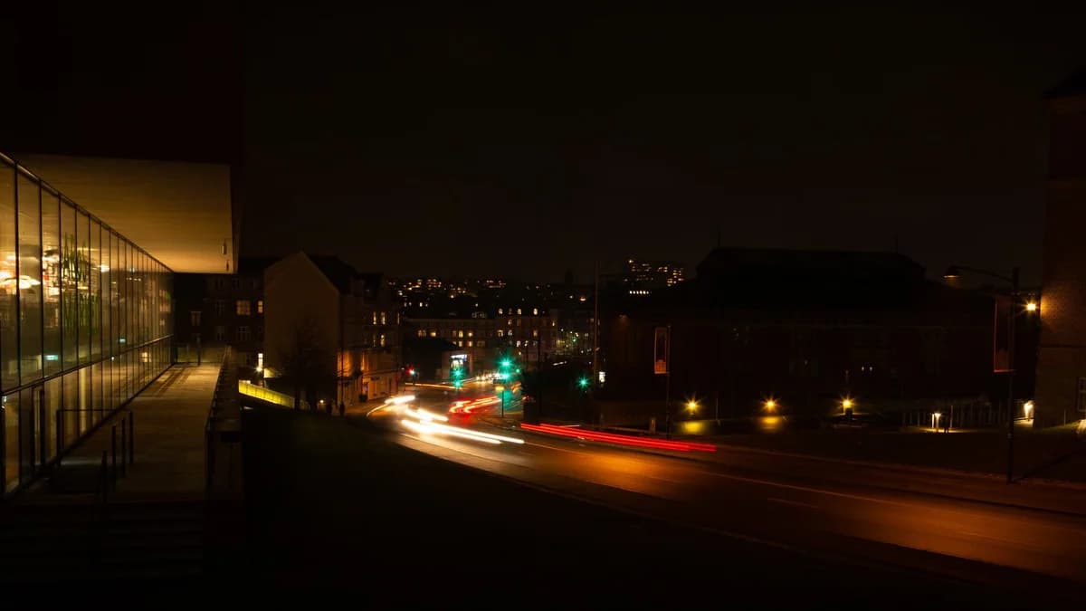 Long-exposure photo of car light trails on a dark city street at night.