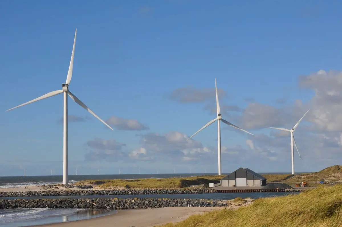 Wind turbines along a sunny Danish coastline near Hvide Sande.