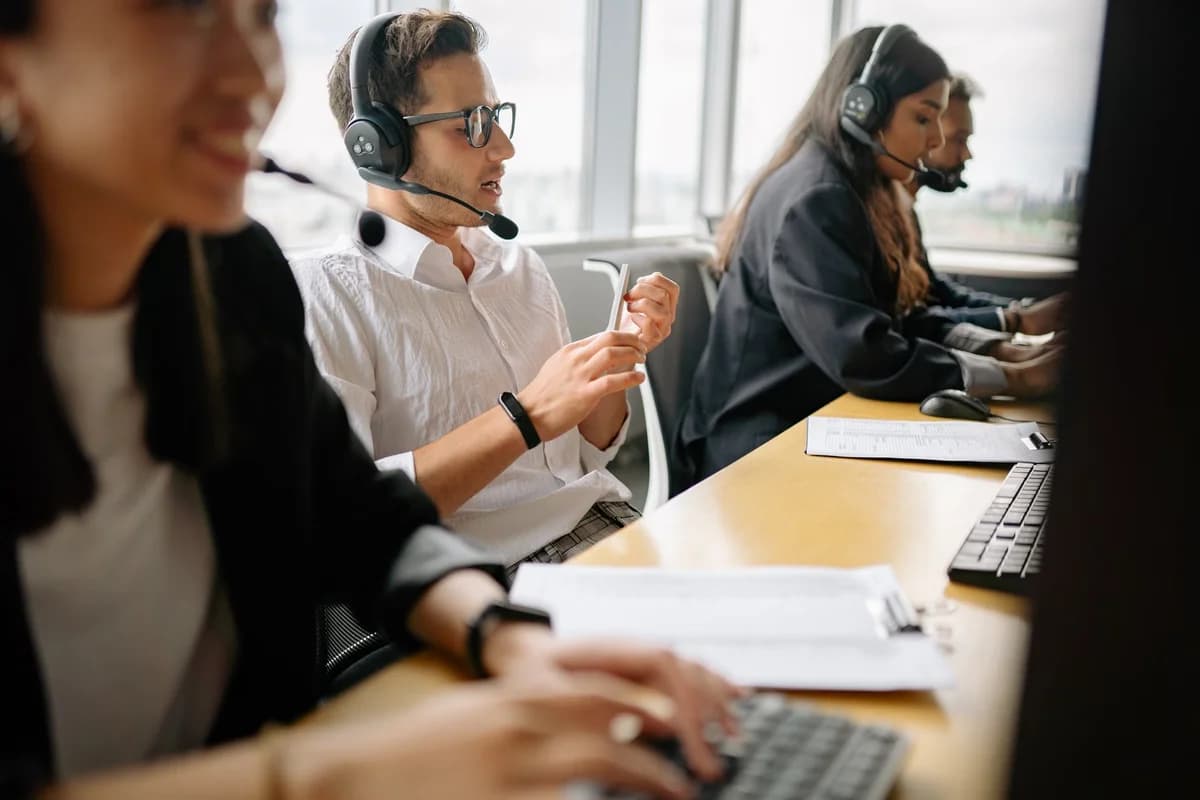 A diverse call center team wearing headsets works together in an office.