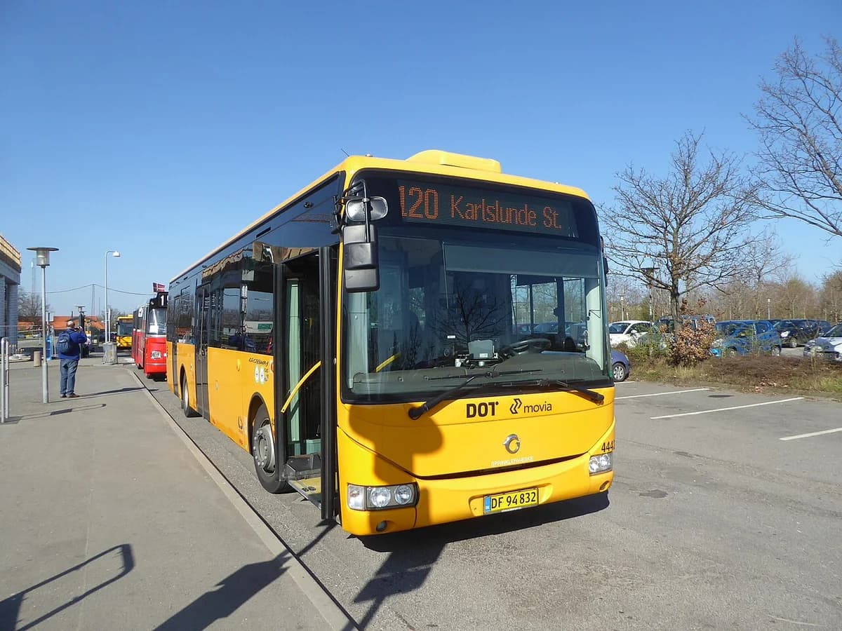 Yellow Movia bus numbered 120 at a station stop.