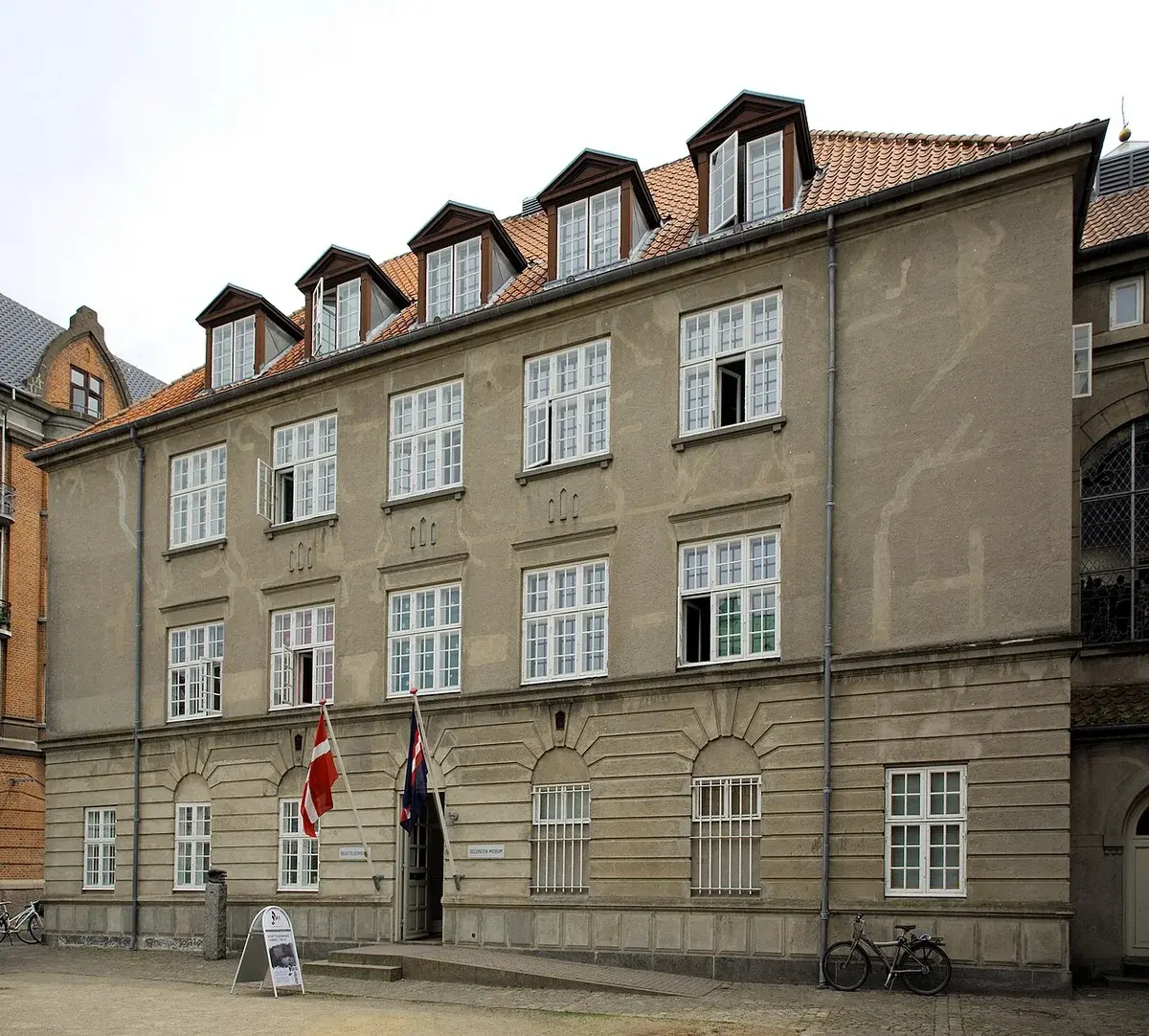 Historic building in Aarhus with Danish flags at the entrance