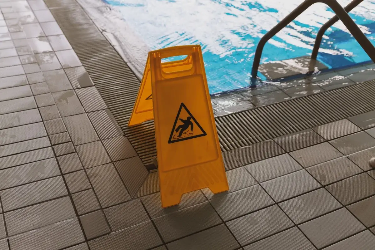 Yellow wet floor warning sign next to an indoor swimming pool