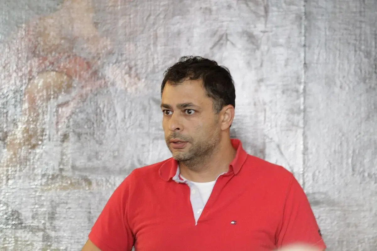 Omar Marzouk standing at a public event in a red polo shirt.