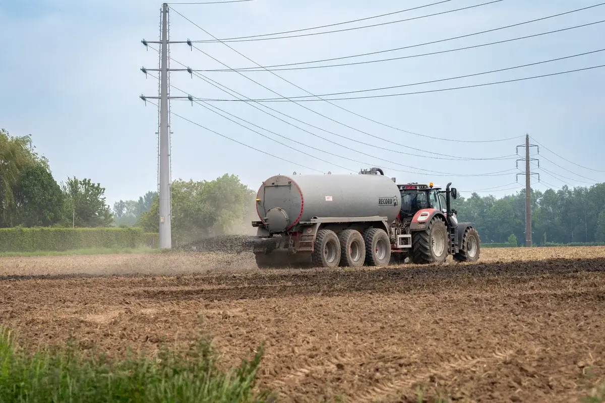 A tractor with a manure tanker spreads liquid fertilizer on a farm field.