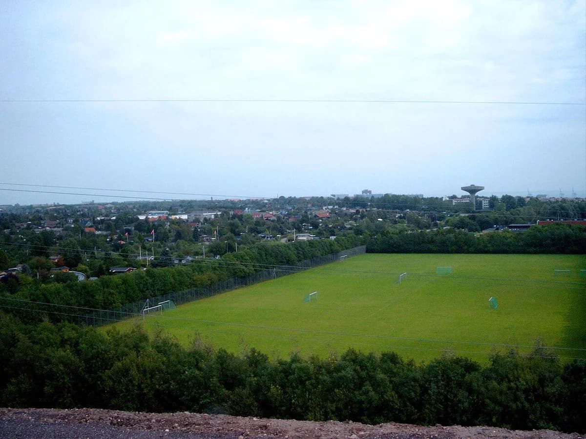 Panoramic view over Aarhus with houses, trees, and a sports field.
