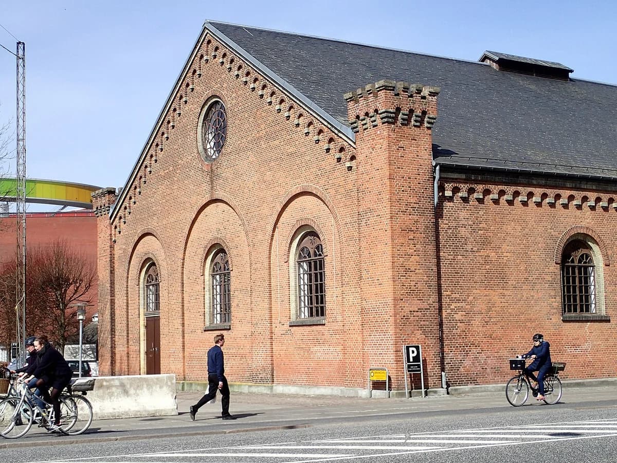 Historic brick building in Aarhus with people biking past.