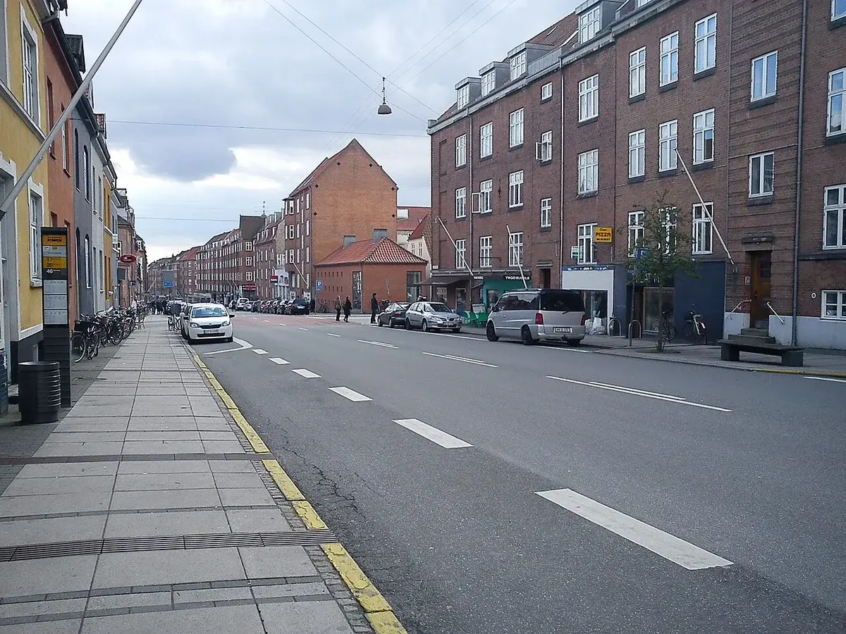A residential street lined with apartment buildings and parked cars in Aarhus.